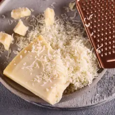 Twardy ser, starty i w kawałkach, na talerzu z tarką. Szukasz, czym zastąpić parmezan?