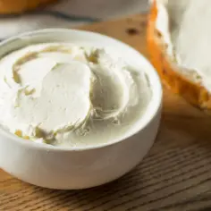 Kremowy serek w miseczce, idealny jako serek philadelphia zamiennik na świeżym pieczywie.