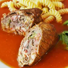 Pyszne rolady wołowe z piekarnika w sosie pomidorowym, podane z makaronem fusilli i świeżymi liśćmi szpinaku z pomidorkiem.