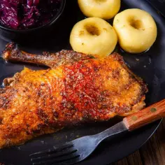 Chrupiąca pieczona gęś z kluskami i czerwoną kapustą. Zastanawiasz się, ile czasu piec gęś, by była idealna?