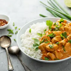 Pyszny kurczak w pomarańczowym sosie z ryżem, idealny, gdy szukasz, czym zastąpić garam masala. Podany z limonką i szczypiorkiem.