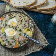 Aksamitny żurek z jajkiem i kiełbasą, idealny do doprawienia czosnkiem, majerankiem i pieprzem. Podany z chlebem.