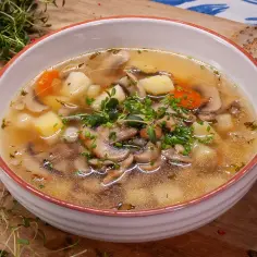 Jak zrobić zupę pieczarkową? Aromatyczna zupa z pieczarkami, ziemniakami i marchewką, udekorowana szczypiorkiem i tymiankiem, podana z chlebem.