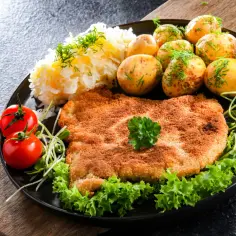 Schabowy na talerzu z ziemniakami i surówką. Idealny kotlet schabowy, jak długo smażyć? Złocisty, chrupiący, z dodatkami.