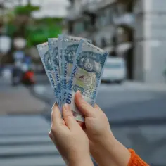 Ręce trzymają pięć banknotów po 1000 forintów. Zastanawiasz się, ile forintów kosztuje obiad na Węgrzech?