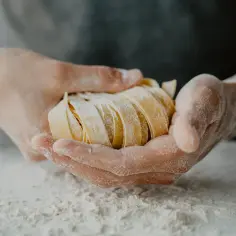 Dłonie trzymają świeży makaron tagliatelle, idealną porcję do przygotowania pysznego dania.