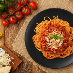Pyszne spaghetti bolognese na talerzu, z pomidorami i bazylią. Idealne, by dowiedzieć się, jak pasteryzować sos do spaghetti z mięsem mielonym.