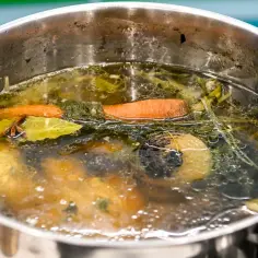Bulion gotuje się w garnku z marchewką, cebulą i liściem laurowym. Liść laurowy w zupie nadaje głębi smaku i aromatu.