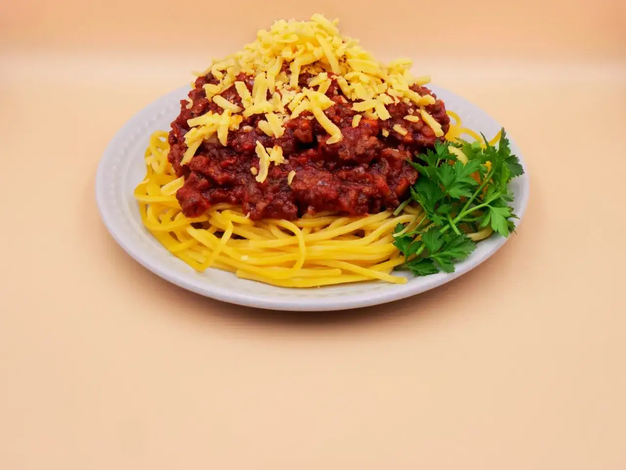 Porcja spaghetti bolognese z tartym serem i natką pietruszki. Zastanawiasz się, ile kcal ma spaghetti bolognese?