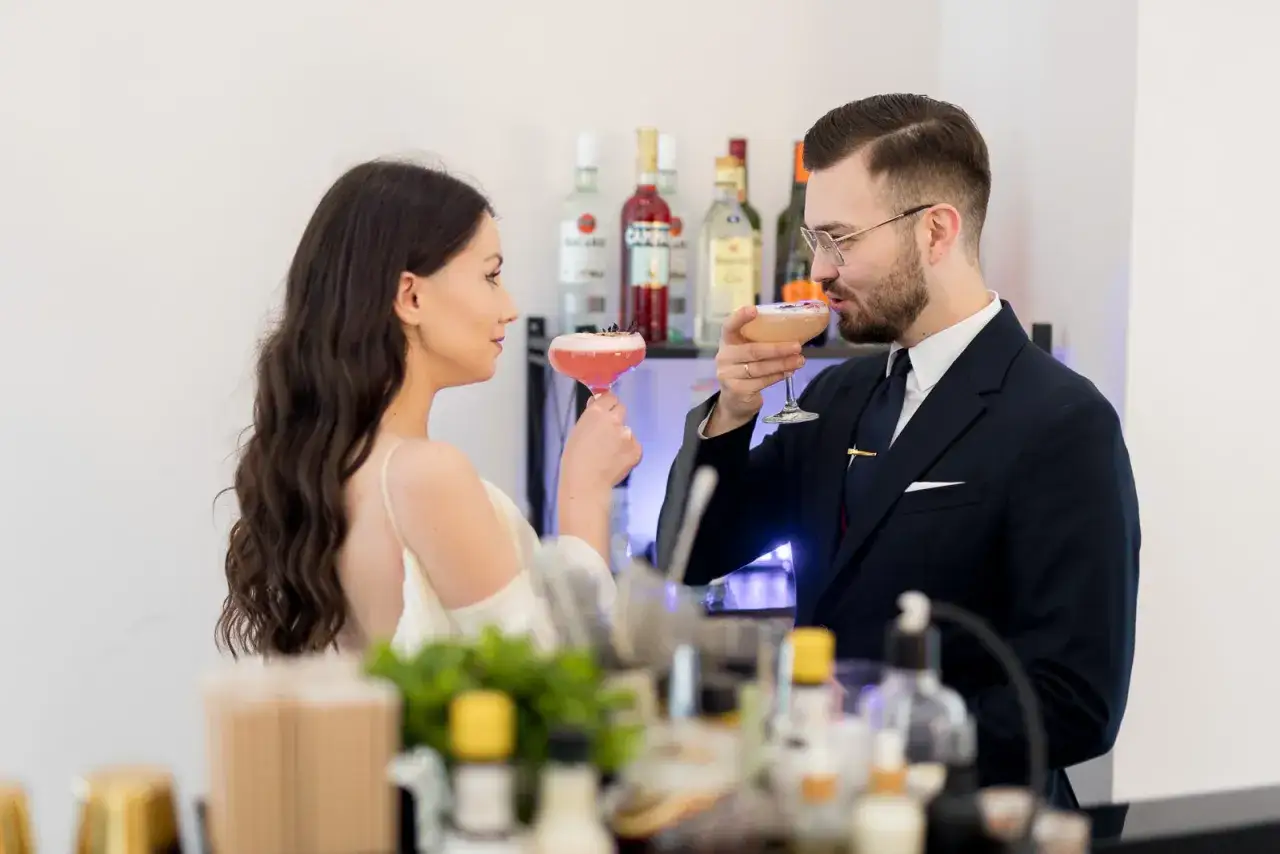 Para młoda i pan młody wznoszą toast drinkami. Zastanawiasz się, ile kosztuje barman na wesele?