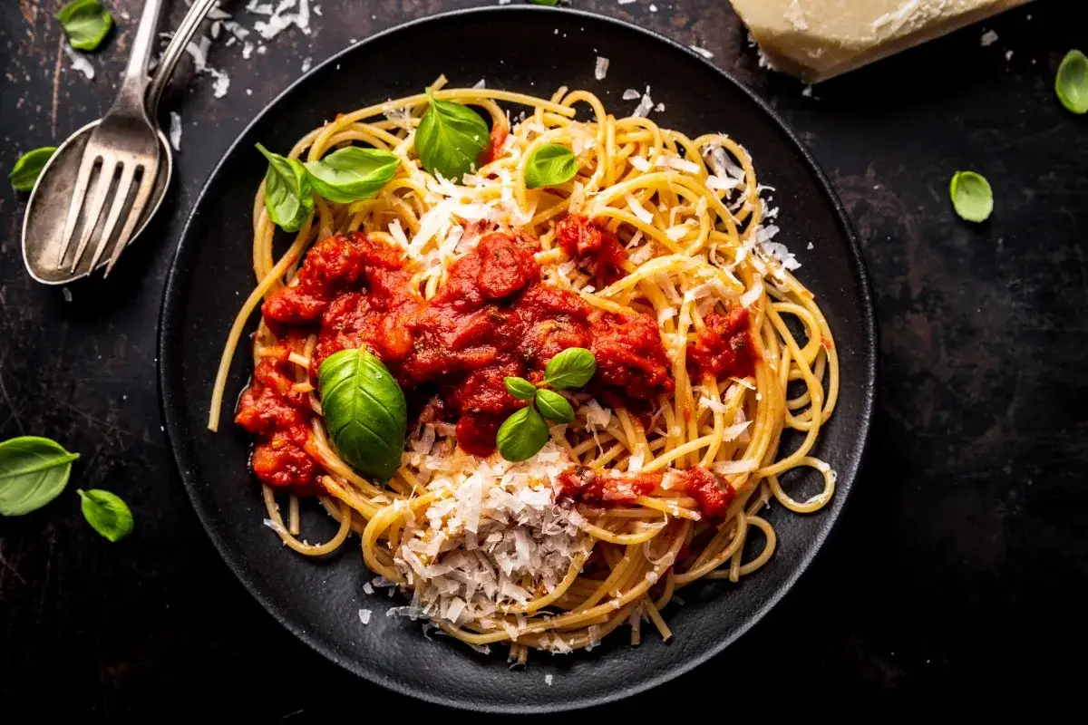Pyszne spaghetti z sosem pomidorowym i parmezanem, ozdobione bazylią. Idealne, gdy chcesz szybko dowiedzieć się, jak zrobić spaghetti ze słoika.
