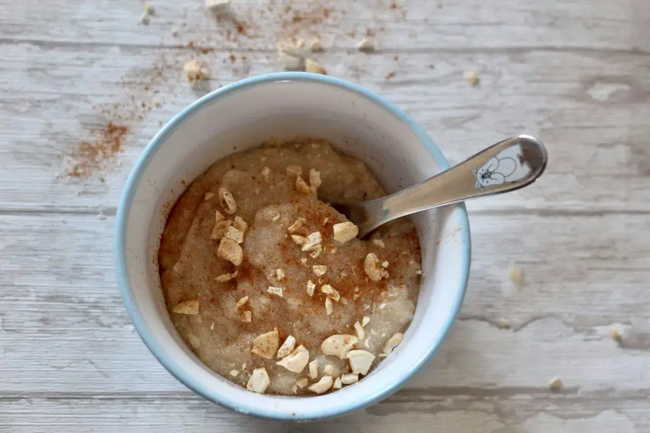 Gotowa kasza jaglana, posypana orzechami i cynamonem, czeka na łyżeczkę z misiem. Idealna na śniadanie!