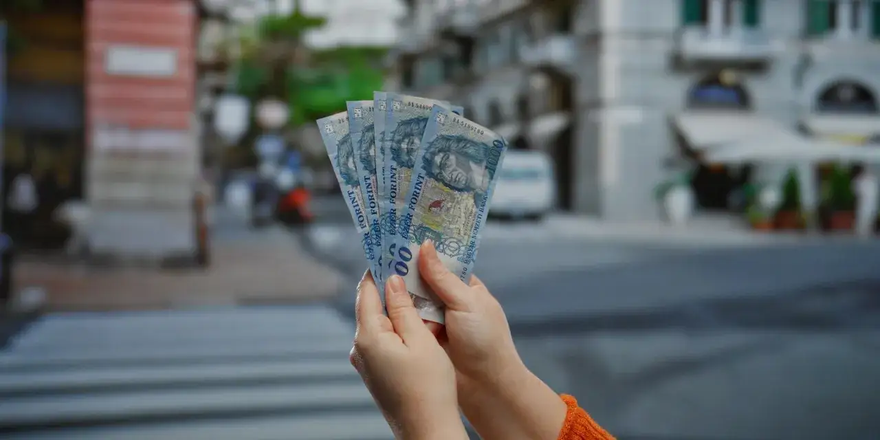 Ręce trzymają banknoty 1000 forintów. Zastanawiasz się, ile forintów kosztuje obiad na Węgrzech?