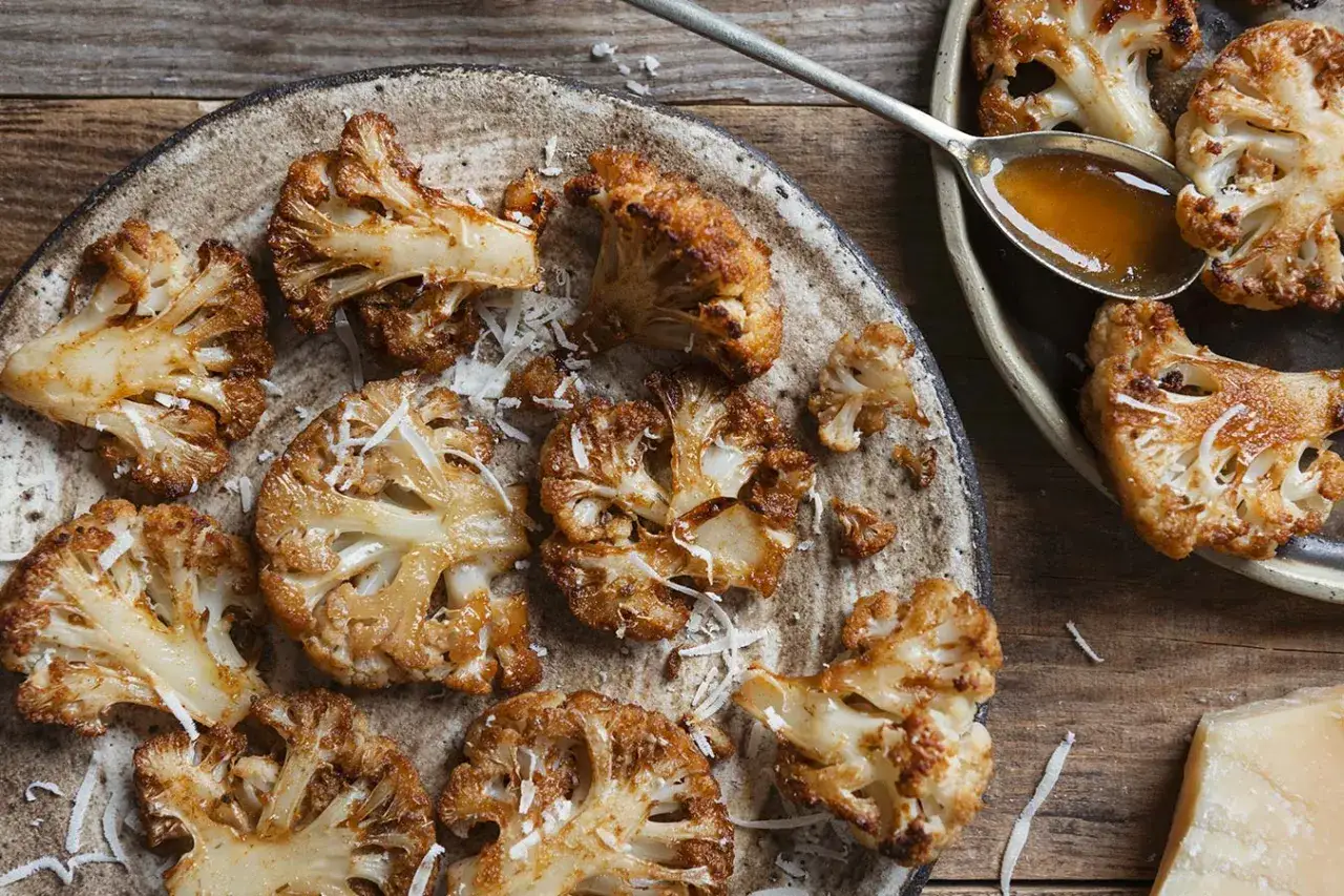 Jak przyrządzić kalafior do obiadu? Pieczone różyczki kalafiora posypane parmezanem, polane sosem.