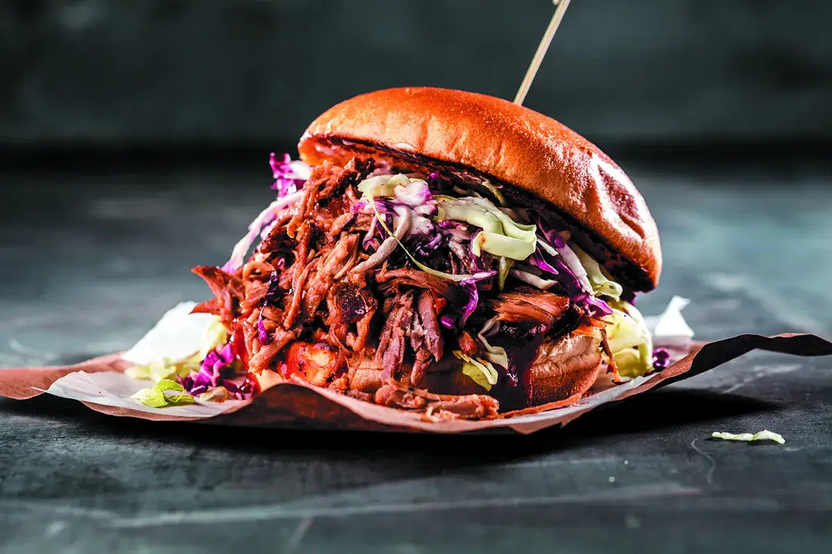 Soczysty burger z szarpaną karkówką i surówką. Idealny pomysł, co zrobić z karkówki na obiad, przepisy na takie dania są proste!