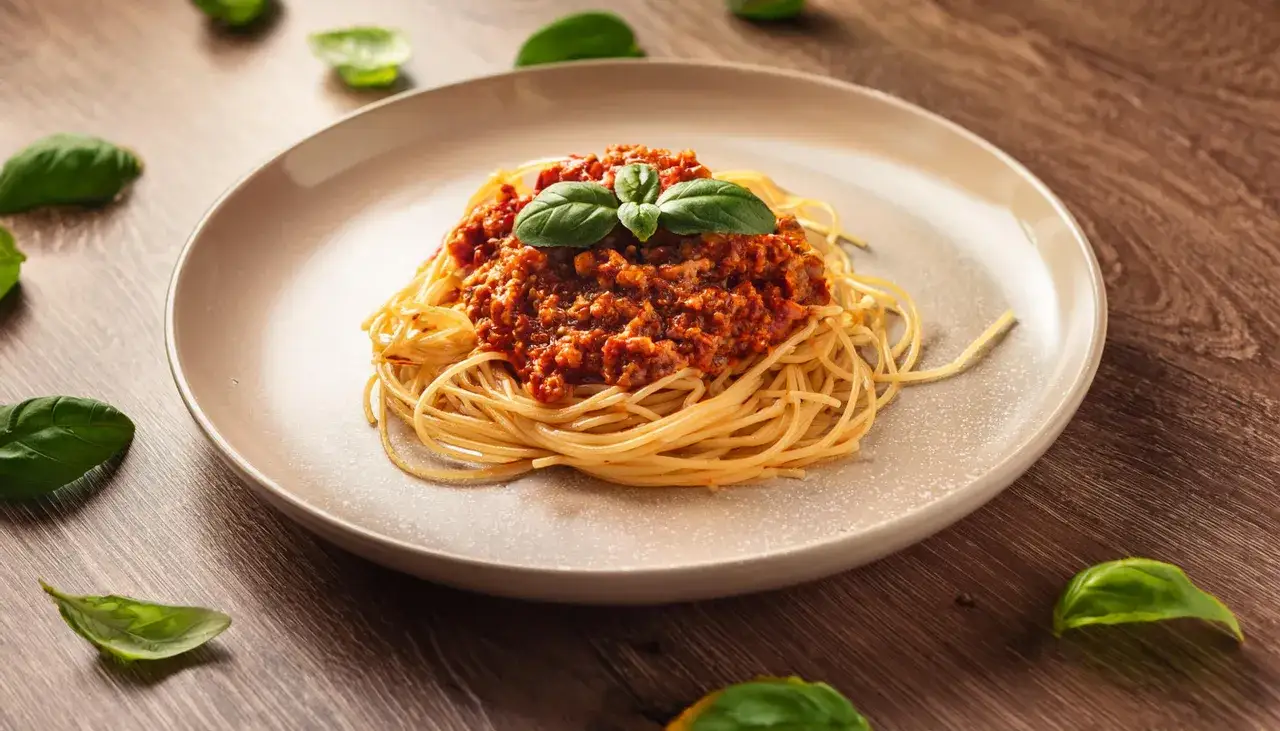 Apetyczne spaghetti bolognese z bazylią na talerzu. Czy to danie jest zdrowe? Zależy od składników!